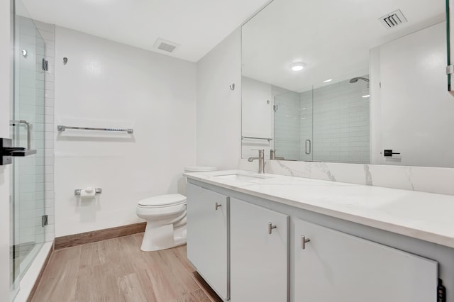 bathroom with hardwood / wood-style flooring, vanity, an enclosed shower, and toilet