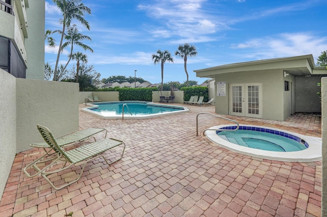 view of pool with french doors, a hot tub, and a patio area