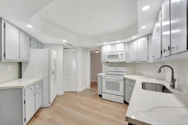 kitchen featuring sink, light hardwood / wood-style flooring, white appliances, light stone countertops, and backsplash