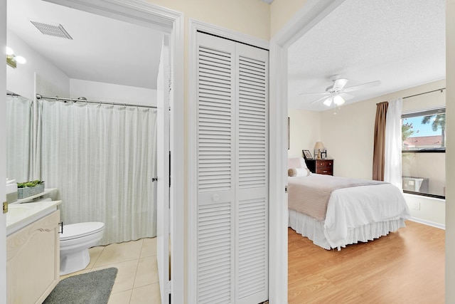 bedroom with ceiling fan, a closet, a textured ceiling, and light tile patterned flooring