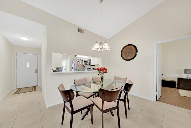 dining area with an inviting chandelier, light tile patterned floors, and high vaulted ceiling