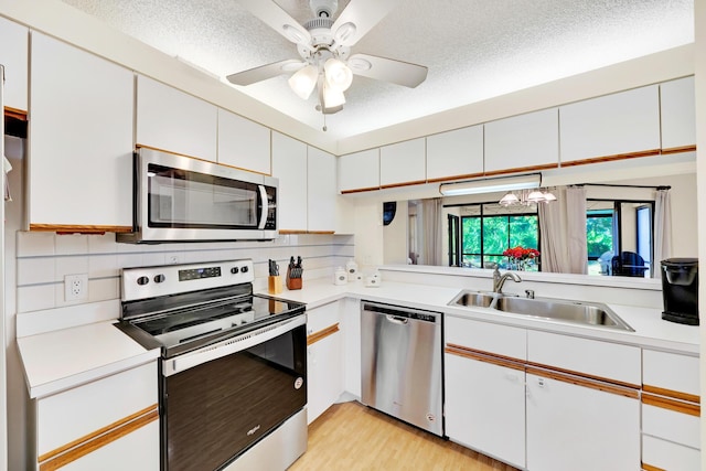 kitchen featuring appliances with stainless steel finishes, sink, white cabinets, and light hardwood / wood-style floors