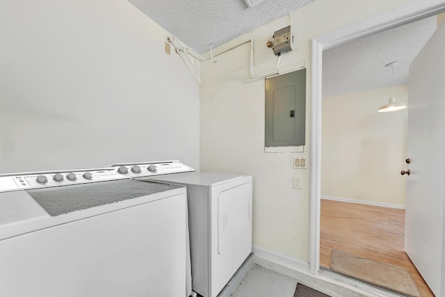 laundry room featuring washing machine and dryer, electric panel, and a textured ceiling