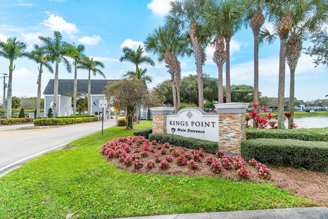 community / neighborhood sign with a water view and a lawn