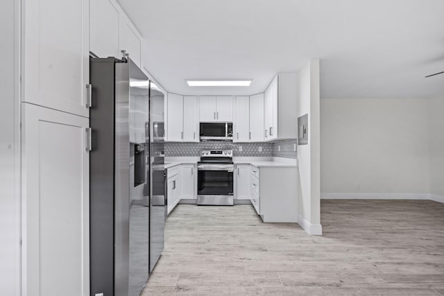 kitchen with tasteful backsplash, white cabinetry, appliances with stainless steel finishes, and light wood-type flooring