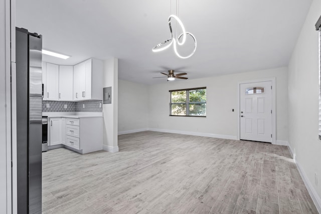 kitchen featuring appliances with stainless steel finishes, white cabinets, light wood-type flooring, and decorative backsplash