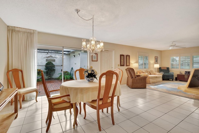 tiled dining area featuring ceiling fan with notable chandelier and a textured ceiling