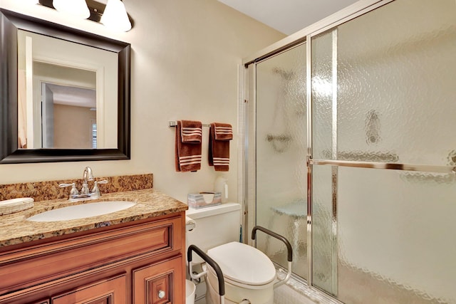 bathroom with a shower with door, vanity, and toilet