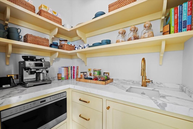 kitchen with sink, cream cabinets, and light stone countertops