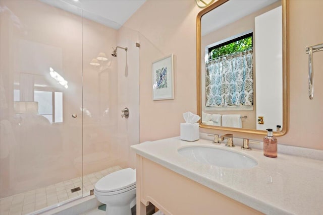 bathroom featuring a shower with door, vanity, and toilet