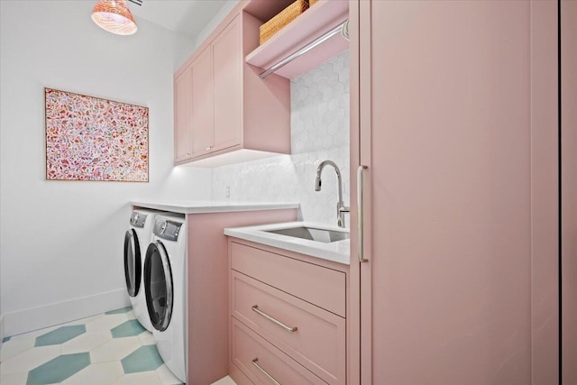 clothes washing area featuring sink, washing machine and dryer, and cabinets