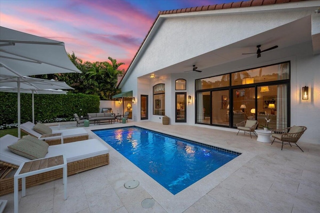 pool at dusk featuring an outdoor hangout area, ceiling fan, and a patio area