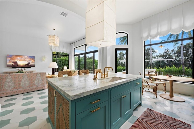 kitchen with decorative light fixtures, sink, and a center island with sink