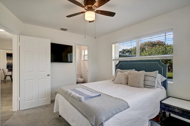 carpeted bedroom with ensuite bath and ceiling fan