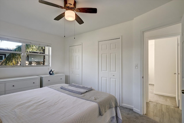 bedroom featuring ceiling fan, light carpet, and two closets