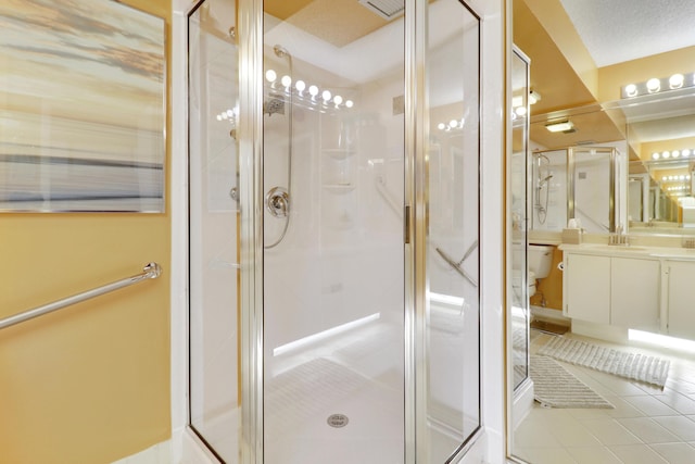 bathroom with a shower with door, vanity, tile patterned flooring, and toilet