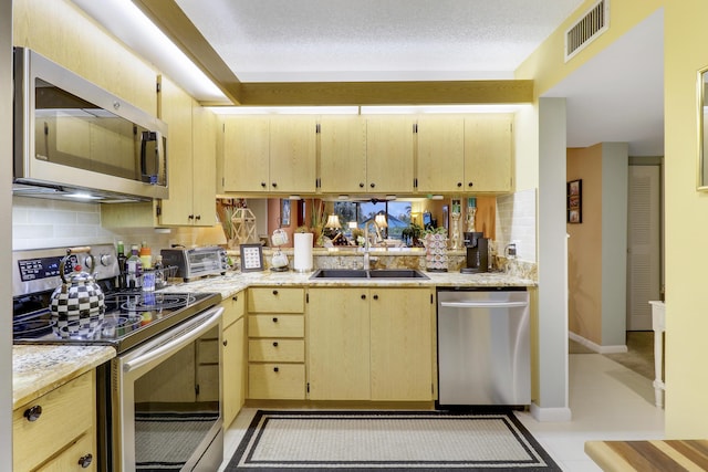 kitchen featuring sink, decorative backsplash, stainless steel appliances, light brown cabinets, and a textured ceiling