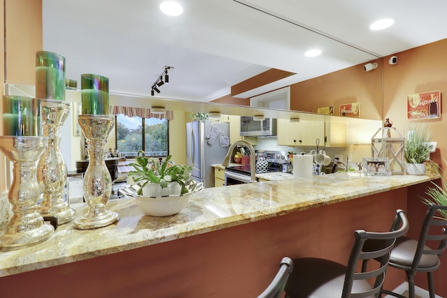 kitchen with light stone countertops, stainless steel appliances, kitchen peninsula, and a breakfast bar