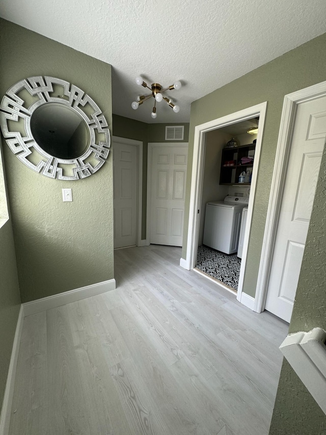 interior space featuring washer and clothes dryer, light hardwood / wood-style flooring, and a textured ceiling