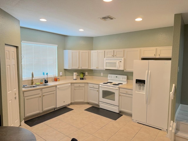 kitchen featuring sink, white appliances, light tile patterned floors, and white cabinets