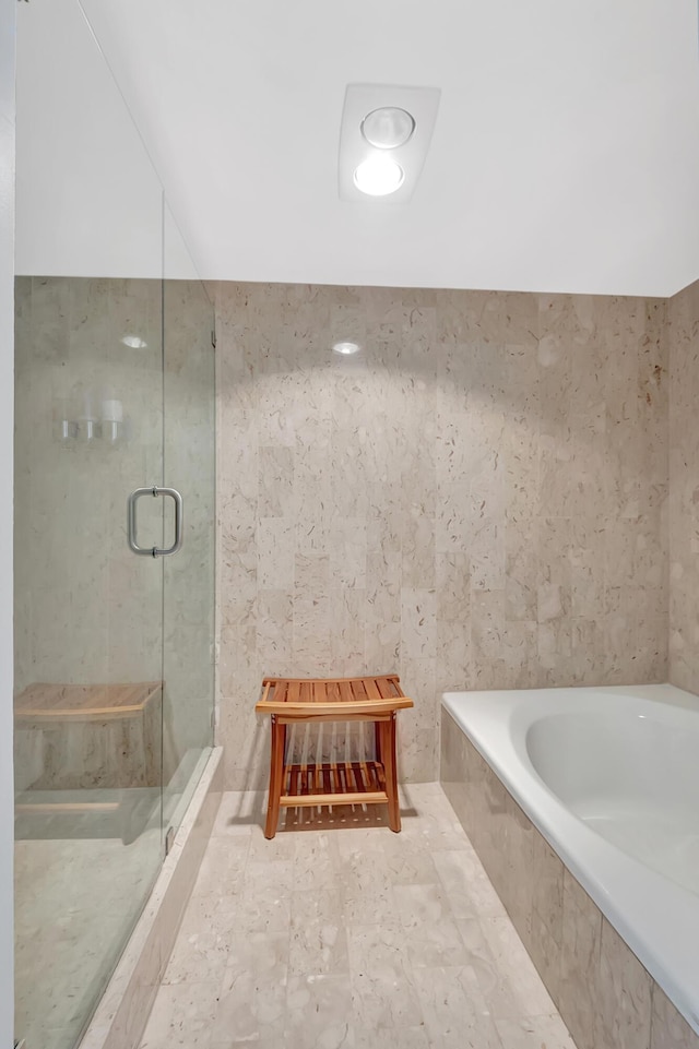 bathroom with tile walls and separate shower and tub