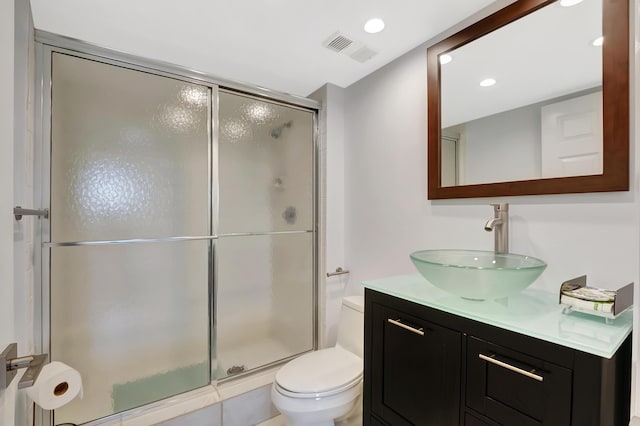 bathroom featuring vanity, toilet, and a shower with shower door