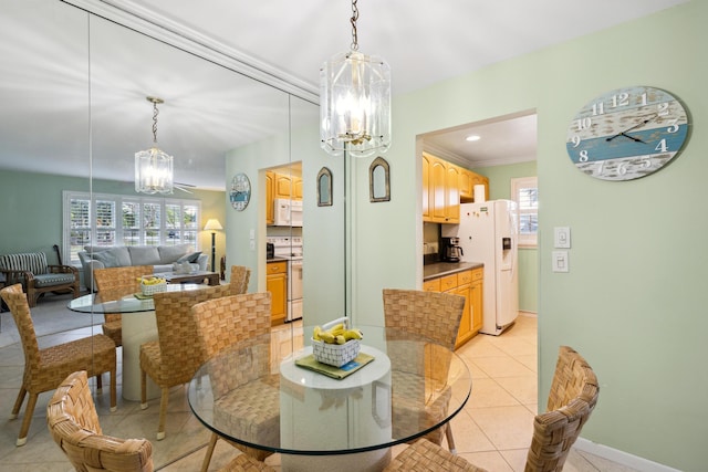 dining area featuring crown molding, a healthy amount of sunlight, a chandelier, and light tile patterned floors