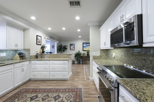 kitchen featuring stainless steel appliances, white cabinetry, and dark stone countertops