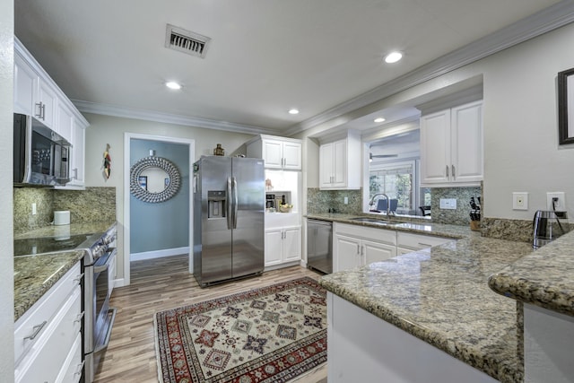 kitchen featuring sink, white cabinetry, light wood-type flooring, ornamental molding, and appliances with stainless steel finishes