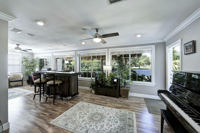 bar with ornamental molding, dark hardwood / wood-style floors, a wealth of natural light, and a textured ceiling