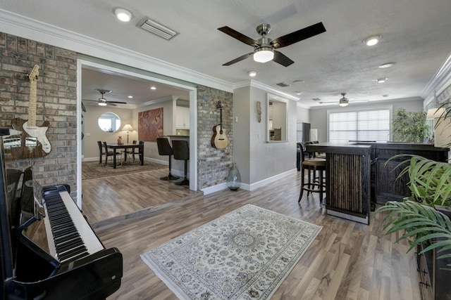 living room featuring light hardwood / wood-style flooring, a fireplace, ornamental molding, a textured ceiling, and brick wall