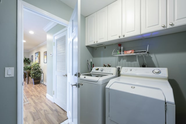 laundry area featuring cabinets, crown molding, light hardwood / wood-style floors, and washer and dryer