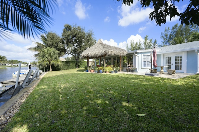 view of yard with a dock, a patio area, french doors, and a water view