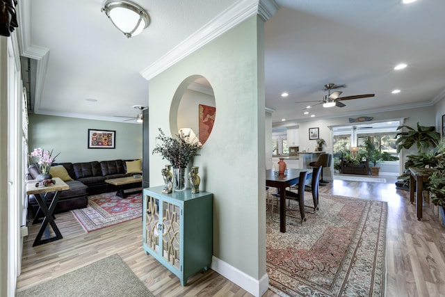 living room with ceiling fan, ornamental molding, and light wood-type flooring