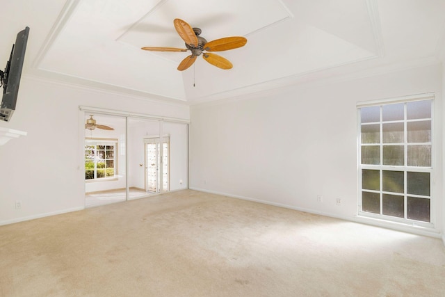 carpeted spare room with a tray ceiling, ornamental molding, and ceiling fan