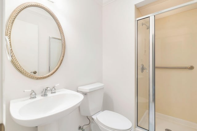 bathroom featuring toilet, a shower with shower door, and sink