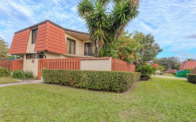 view of side of home with a balcony and a yard