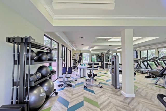 exercise room featuring light parquet floors, ornamental molding, and a tray ceiling