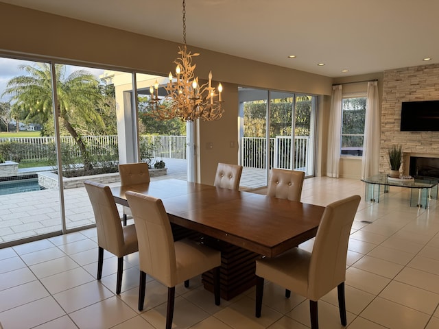 dining space with a fireplace, a chandelier, a healthy amount of sunlight, and light tile patterned flooring