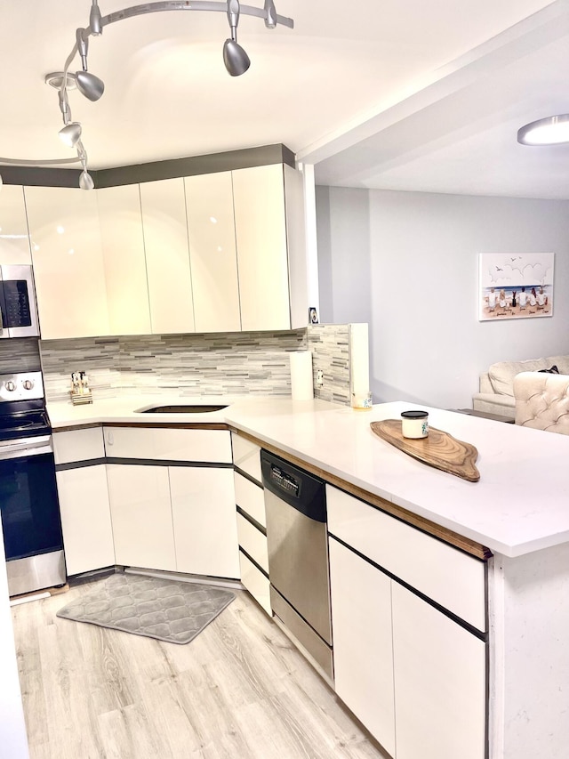 kitchen featuring appliances with stainless steel finishes, kitchen peninsula, light hardwood / wood-style floors, and white cabinets