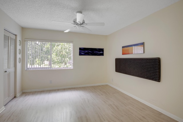 unfurnished room featuring ceiling fan, a textured ceiling, and light wood-type flooring