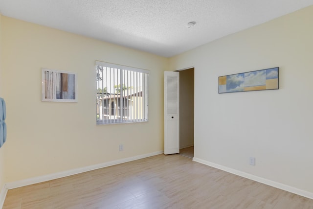 spare room with a textured ceiling and light hardwood / wood-style flooring