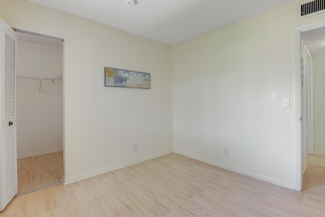 unfurnished bedroom with a walk in closet, light hardwood / wood-style floors, and a closet