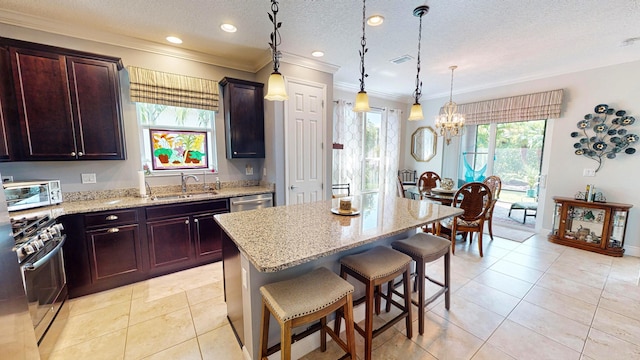 kitchen with sink, appliances with stainless steel finishes, a kitchen breakfast bar, a kitchen island, and decorative light fixtures