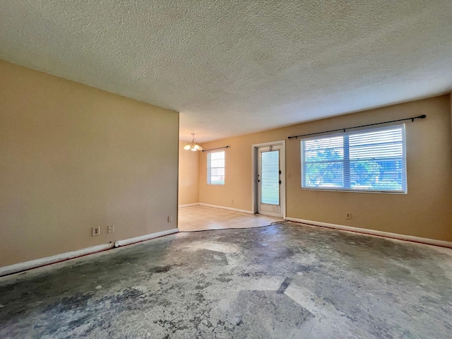 spare room with an inviting chandelier and a textured ceiling