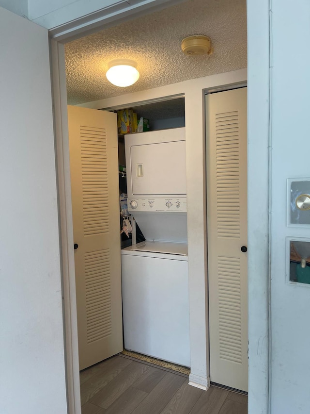 clothes washing area with stacked washer and clothes dryer, dark wood-type flooring, and a textured ceiling