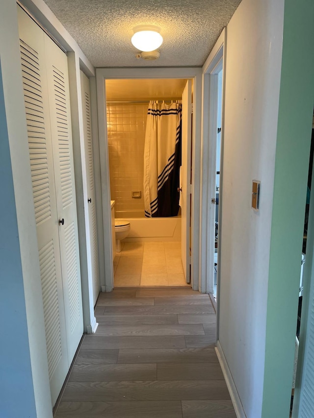 corridor featuring dark hardwood / wood-style floors and a textured ceiling