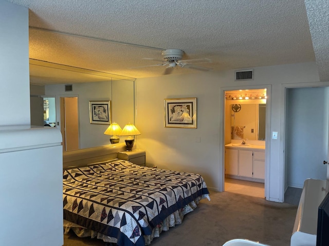 bedroom featuring ensuite bathroom, carpet, and a textured ceiling