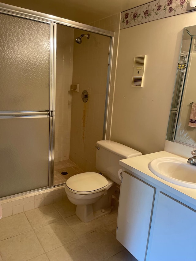 bathroom with vanity, toilet, tile patterned floors, and a shower with shower door