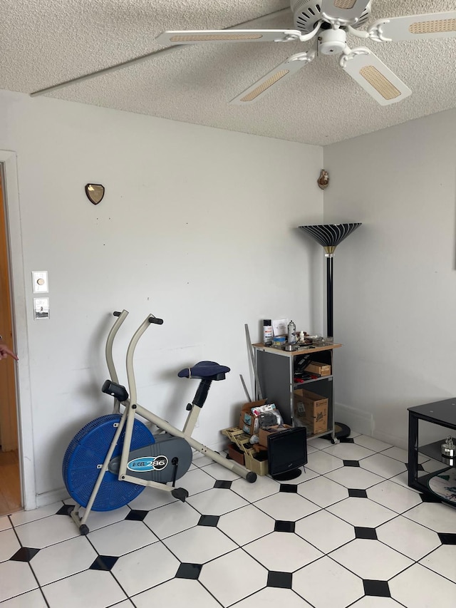 exercise area with ceiling fan and a textured ceiling